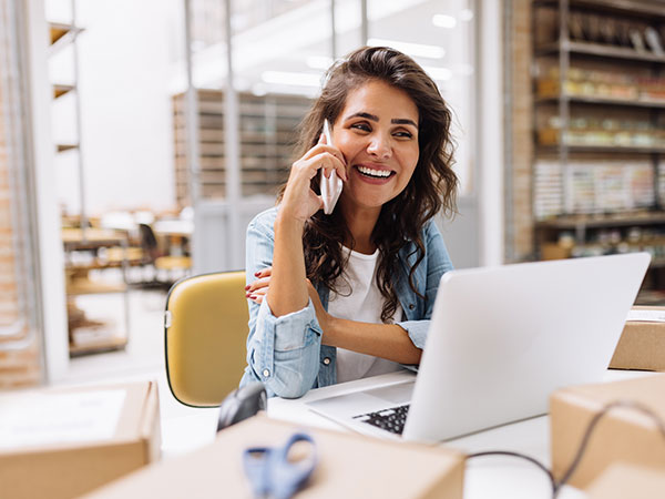 woman talking on a phone in front of her laptop