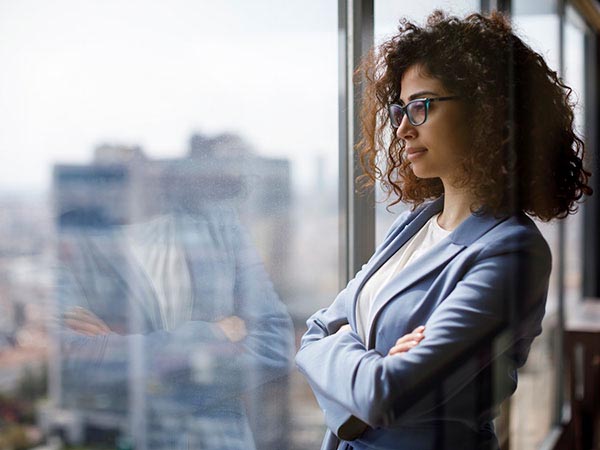 a woman standing in front of a window showing her reflection