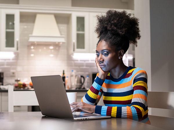 a woman siting at her kitchen table on her laptop