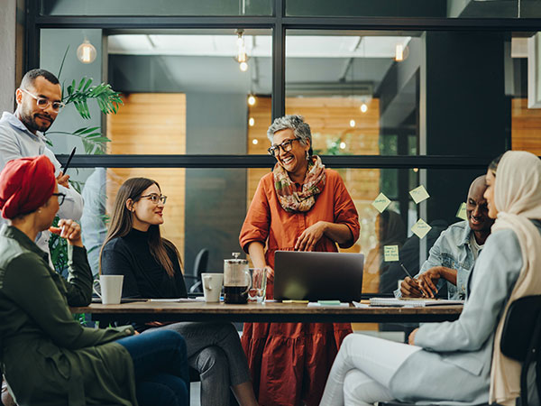 a team of coworkers represented by various ages, genders and races conducting a meeting.