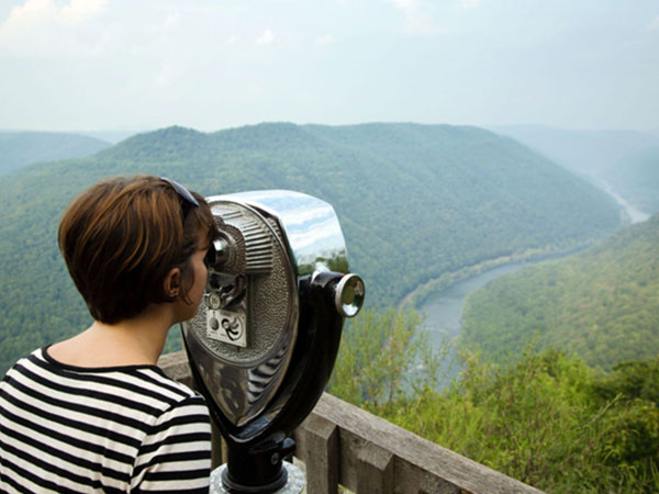 woman looking through a viewing machine at a scenic vista