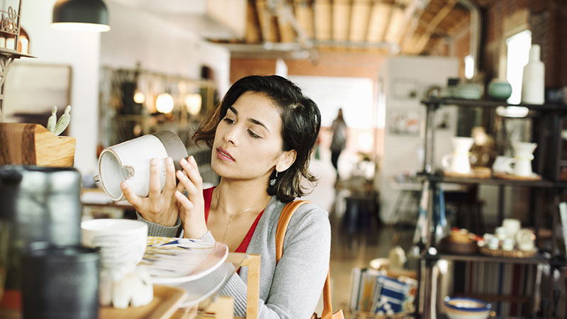 Woman in a shop checking the bottom of a piece of pottery