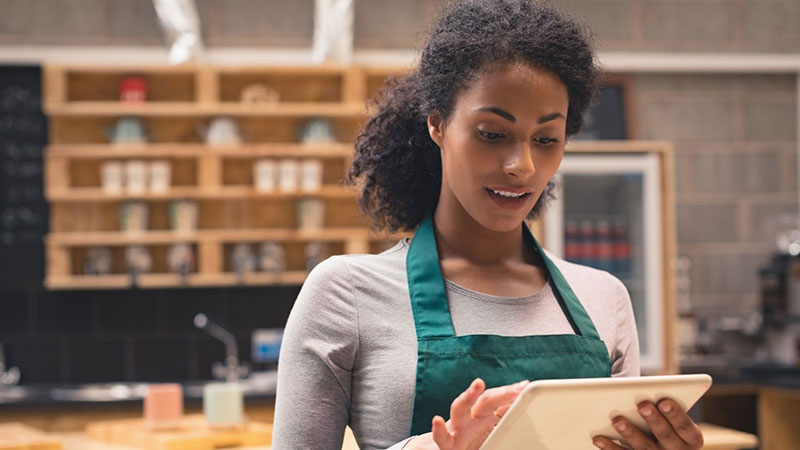 Woman wearing an apron using a tablet for a transaction