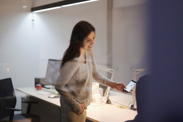 Woman sharing idea on smart phone with coworker in office