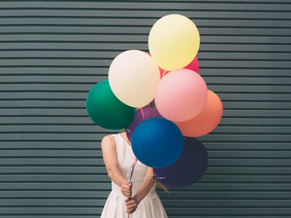 woman holding a bunch of colorful balloons in front of her face