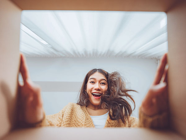 View up from inside a box at an excited woman looking at what's inside