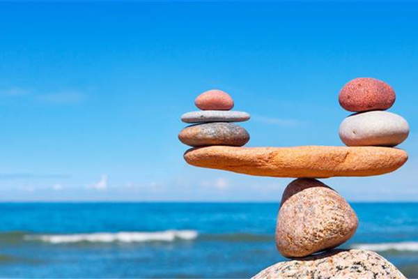 Balanced stack of smooth stones by the ocean under a clear blue sky