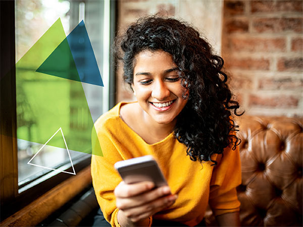 A woman smiling as she reads a message on her phone