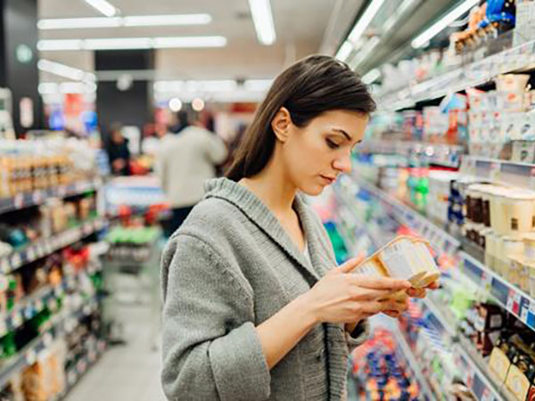 young woman shopping in the supermarket grocery store.Reading ingredients,declaration or expiration