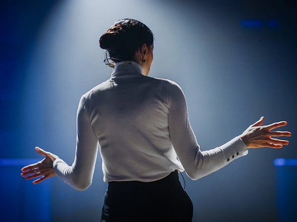 Woman speaking on stage facing audience