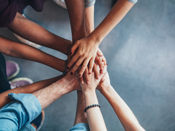 A diverse group of hands join together in unity and teamwork