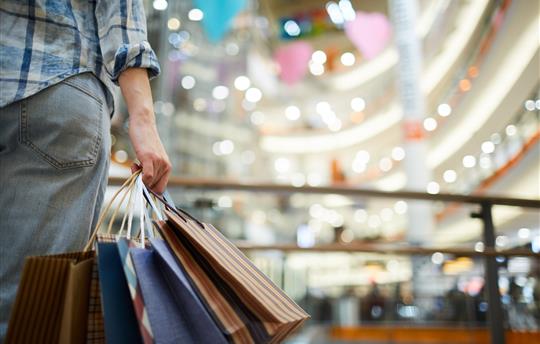 Man shopping in large mall with shopping bags