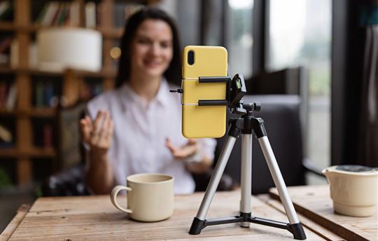 Young millennial or gen z woman with long brunette hair streaming with smart phone