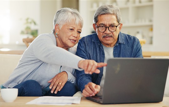 Senior, couple and planning on laptop in living room with document for finances, investment