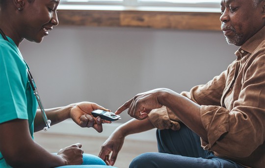 Senior man having his blood sugar measured in a nursing home by his caregiver.