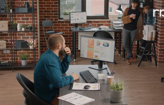 Man sitting at a desk reviewing data on a large computer screen
