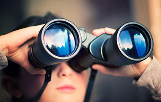 young boy looking through large binoculars