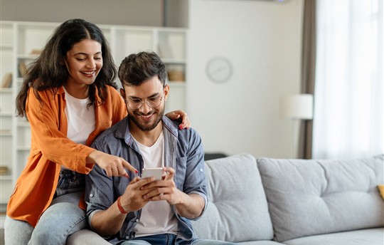 man and woman smiling at phone