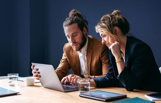 two marketers sharing a laptop