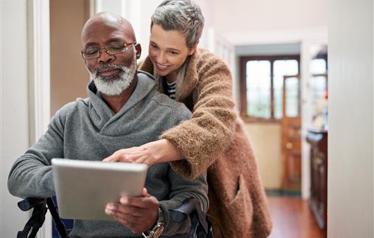 man and woman looking at ipad in hallway, smiling