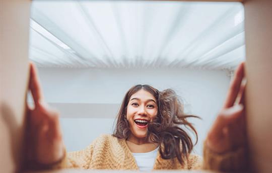 View up from inside a box at an excited woman looking at what's inside