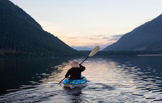 a lone person kayaking on a mountain lake